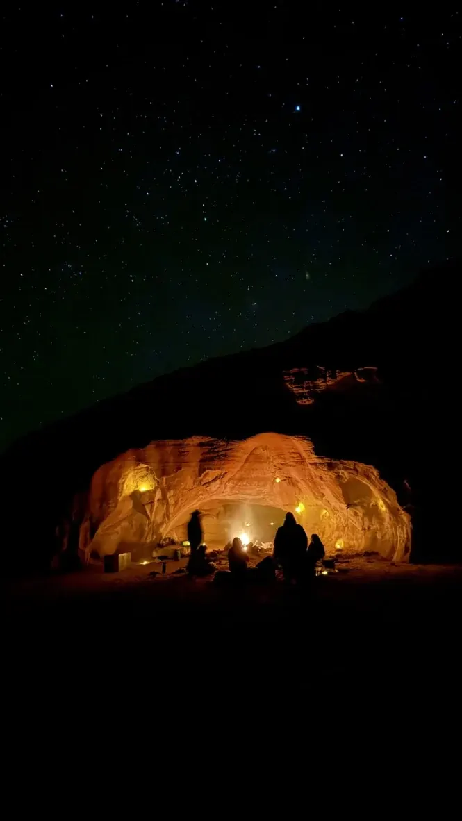Una cueva con iluminación cálida bajo un cielo estrellado