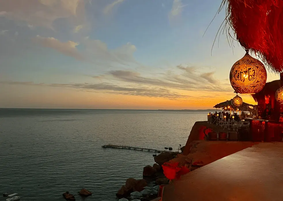 La terraza de Farsha iluminada por faroles, con vistas al mar al atardecer