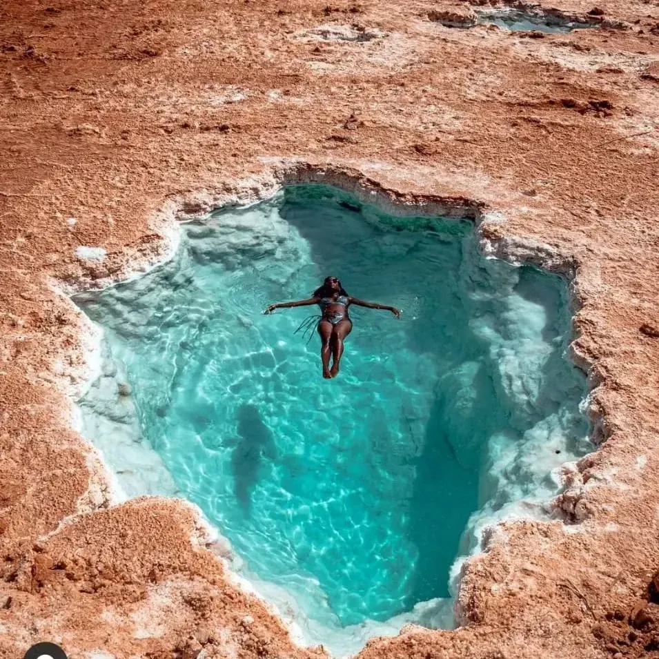 Viajero flotando en una piscina de sal turquesa en Siwa