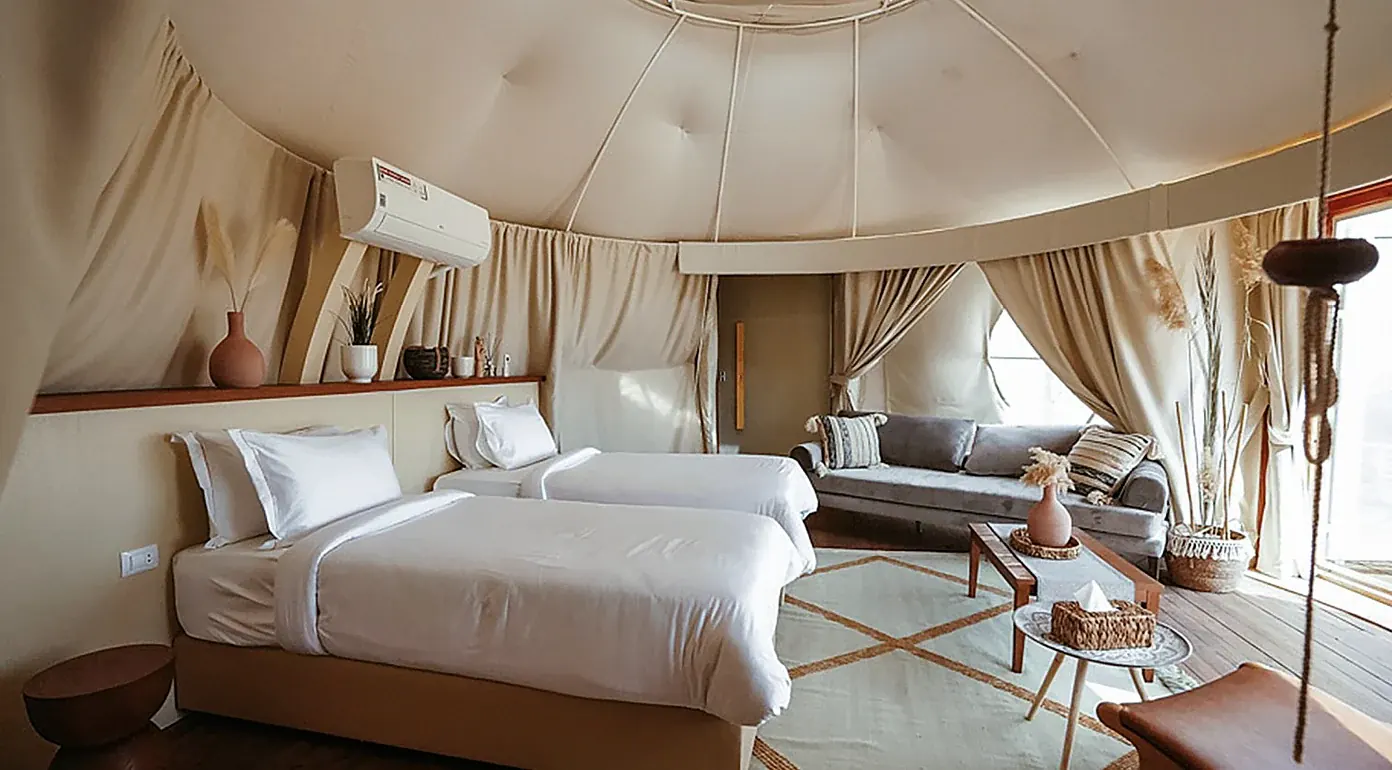 Camas individuales y zona de estar en una tienda de glamping de Remal El Rayan